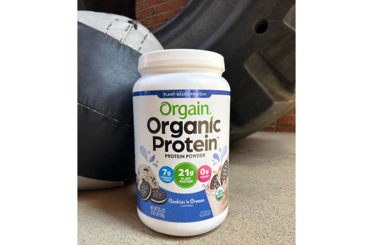 A tub of Orgain organic protein powder in Cookies 'n Cream flavor  on the floor of a Crossfit gym